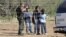 FILE - A Border Patrol agent stands at a ranch fence line with children taken into custody in southern Texas brush country north of Laredo.