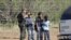 FILE - A Border Patrol agent stands on a ranch fence line with children taken into custody, in South Texas brush country north of Laredo, Texas.