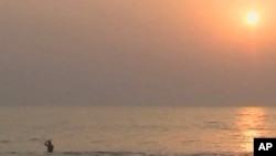 A tourist wades in the water at a beach in Sierra Leone