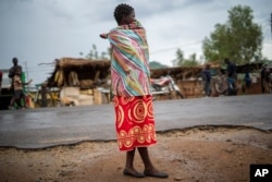 FILE - A woman stands outside the health clinic in the village of Migowi, Malawi, Dec. 10, 2019.