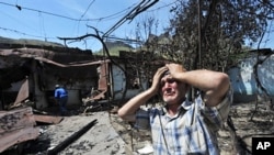 An ethnic Uzbek holds his head in his hands as he stands beside the wreckage of his burned out home in Osh (file photo – 14 June 2010)