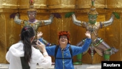 Seorang turis dari China berpose di depan Grand Palace di Bangkok.