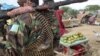 A fruit seller looks across as a Somali government soldier stands guard in Afgoye, west of the capital Mogadishu, in Somalia on June 7. A recent survey conducted by VOA's Somali Service reveals widespread agreement on many key provisions of the draft cons