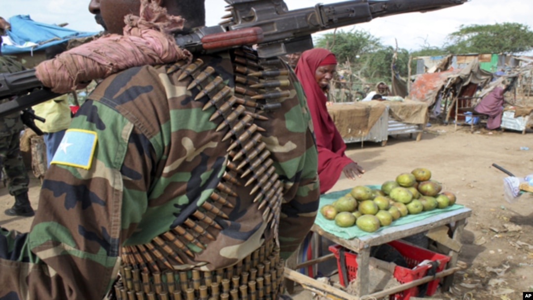 A fruit seller looks across as a Somali government soldier stands guard in Afgoye, west of the capital Mogadishu, in Somalia on June 7. A recent survey reveals widespread agreement on many key provisions of the draft constitution.