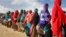 Women who fled drought queue to receive food distributed by local volunteers at a camp for displaced persons in the Daynile neighborhood on the outskirts of Mogadishu, in Somalia, May 18, 2019. 