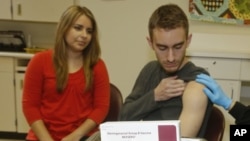 FILE - Meningococcal meningitis survivor and vaccination advocate Leslie Meigs looks on as her brother Andrew (18), a college student in Texas, receives Bexsero(R), a meningococcal group B vaccine approved by the FDA for ages 10-25. Feb. 24, 2015.