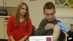FILE - Meningococcal meningitis survivor and vaccination advocate Leslie Meigs looks on as her brother Andrew (18), a college student in Texas, receives Bexsero(R), a meningococcal group B vaccine approved by the FDA for ages 10-25. Feb. 24, 2015.