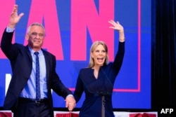 El candidato presidencial independiente Robert F. Kennedy Jr. (izq.) saluda a una multitud que lo vitorea junto a su esposa, la actriz Cheryl Hines, durante un evento de campaña en el Centro de eventos Henry J. Kaiser en Oakland, California, el 26 de marzo de 2024.