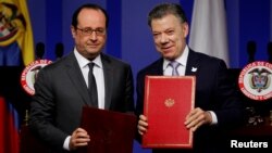 France's President Francois Hollande (L) and his Colombian counterpart Juan Manuel Santos pose for photographs with signed agreements during a joint news conference at the presidential palace in Bogota, Colombia, Jan. 23, 2017. 