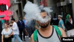 A man uses a vape as he walks on Broadway in New York City, September 9, 2019.
