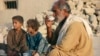 A survivor of an earthquake sits with his children as he drinks tea near the rubble of a mud house which collapsed following an earthquake in the town of Awaran, in the south-western Pakistani province of Baluchistan, September 27, 2013. The death toll fr