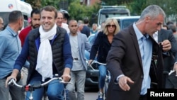 Presiden Perancis Emmanuel Macron dan istrinya Brigitte Trogneux (tengah) bersepeda dari rumah mereka di Le Touquet, Perancis, di malam sebelum pemilu legislatif putaran pertama, 10 Juni 2017. 