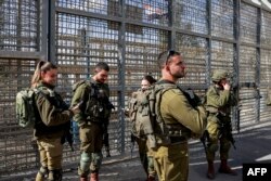 FILE - Israeli army soldiers stand next to the border fence with Egypt at the Nitzana border crossing in southern Israel on January 30, 2024, as Israeli demonstrators gather to block humanitarian aid trucks from entering into Israel on their way to the Gaza Strip.