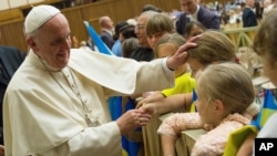 Pope Francis caresses a child during his weekly general audience, in the Pope Paul VI hall, at the Vatican, Aug. 19, 2015.