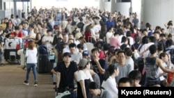 Passengers stranded at Kansai International Airport by Typhoon Jebi line up outside the airport as they wait for the arrival of a special bus service to transport them out of the area, in Izumisato, Japan, Sept. 5, 2018.