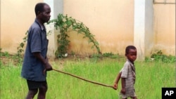 FILE - A child leads a man affected by river blindness in Gbarnga, Liberia, Sept. 4, 1995. 