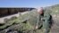 FILE - Border Patrol agent Richard Gordon, a 23-year veteran of the agency, examines broken dried branches that indicate human traffic near the border fence where illegal immigrants enter the United States in the Boulevard area east of San Diego, California, March 25, 2013.