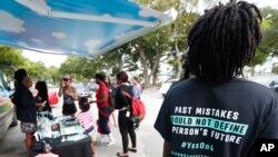 FILE - people gather around the Ben & Jerry's "Yes on 4" truck as they learn about Amendment 4 and eat free ice cream at Charles Hadley Park in Miami. 