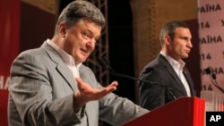 Ukrainian presidential candidate Petro Poroshenko, left, talks with Vitali Klitschko, at right, during a press conference, in Kyiv, Ukraine, May 26, 2014. 