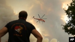 A helicopter flies over a wildfire in Giannouli, in the Evros region of Greece, on Aug. 31, 2023. Greek authorities have reinforced firefighting forces in the country's northeast, where a massive blaze in its 13th day has flared up again. (e-evros.gr via AP)