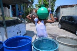 Un residente de la colonia Los Almendros, en Ciudad Delgado, El Salvador, porta un contenedor con agua recibida de la Cruz Roja como parte del esfuerzo para prevenir un mayor contagio del COVID-19, el 8 de abril de 2020.