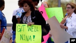 A Texas Health Presbyterian Hospital Dallas staff carries a sign wishing Nina Pham well as she and others wait for an ambulance carrying Pham to depart for Maryland, October16, 2014.