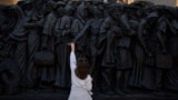 A girl touches the "Angels Unaware" boat sculpture by Canadian artist Timothy P. Schmalz placed at St. Peter's square in Rome, March 7, 2025. 