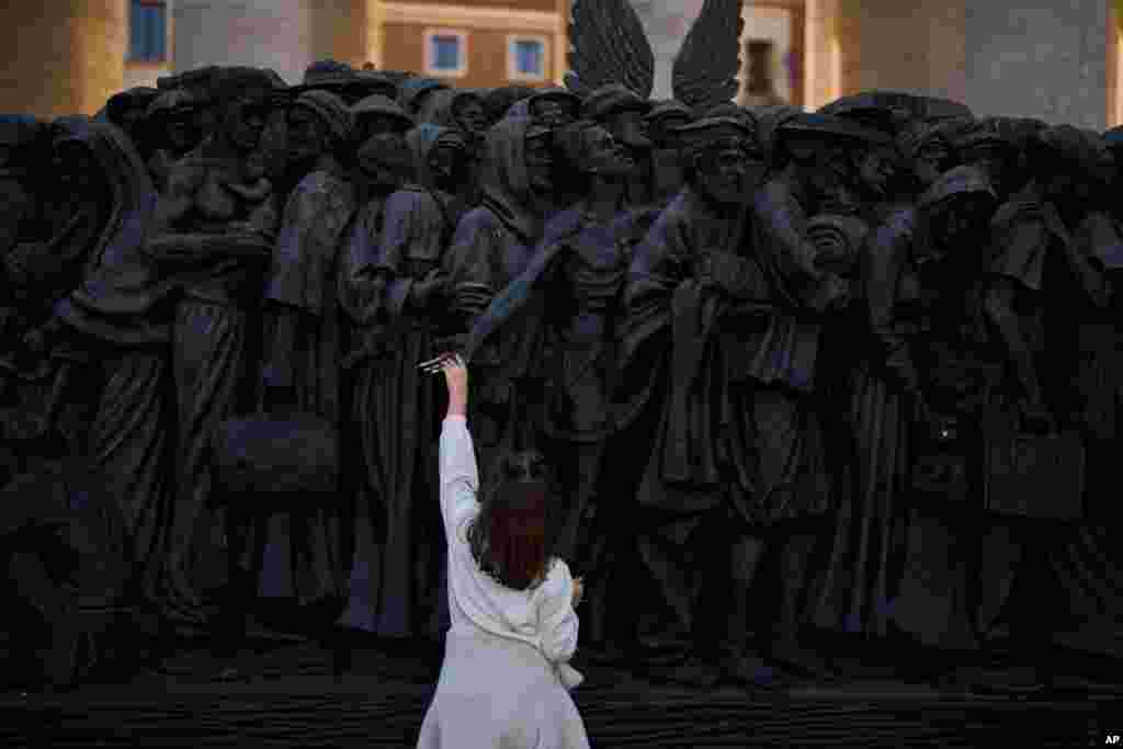 Seorang gadis menyentuh patung perahu &quot;Angels Unaware&quot; karya seniman Kanada Timothy P. Schmalz yang ditempatkan di lapangan Santo Petrus di Roma, Italia. (AP)&nbsp;&nbsp;