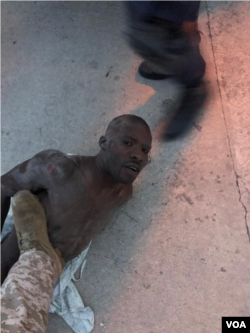 Alleged gang leader Arnel Joseph lies on the ground as police puts boot on his chest.