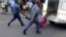 A picture grabbed on an amateur video and released by the South African Daily Sun newspaper shows South African policemen holding the legs of a Mozambican taxi driver handcuffed to the back of a police van while being dragged by the van in Daveyton, Feb. 