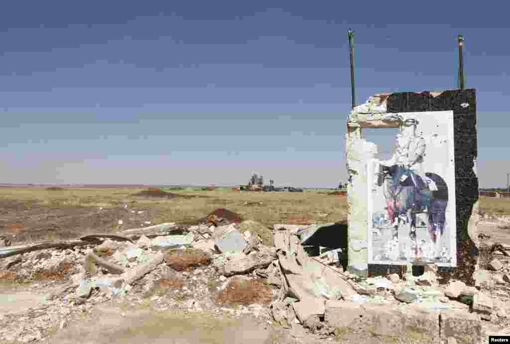 A defaced picture of Bassel al-Assad, brother of Syria's President Bashar, is seen at the gate of the Minnig military airport after it was seized by rebels, August 8, 2013.