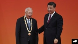 Former Hong Kong Chief Executive Tung Chee-hwa, left, stands with Chinese President Xi Jinping after receiving an award at a ceremony in Beijing's Great Hall of the People, Sept. 29, 2019. 