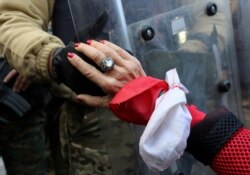 A protester holds the hand of a Lebanese army soldier during a protest against the political elite in Beirut, Jan. 27, 2020.