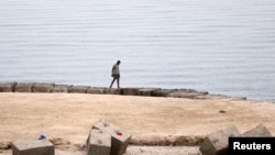 FILE - A man walks along one of the beaches that have been closed after a Russian citizen was killed in a shark attack near a beach at the Egyptian Red Sea resort of Hurghada, June 9, 2023.