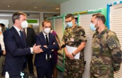 FILE - French Health Minister Olivier Veran (L) and French Overseas Minister Sebastien Lecornu (2nd L) talk with military medical staff during a visit at the CHU hospital in Fort-de-France, Martinique, on Aug. 12, 2021.