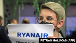 Uma mulher com um cartaz que diz "Onde está Roman (Protasevich)?!" à chegada de avião da Ryanair 