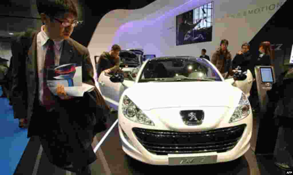 People gather around a Peugeot RCZ sports coupe on display during the Tokyo Motor Show in Tokyo Friday, Dec. 2, 2011. (AP Photo/Junji Kurokawa)