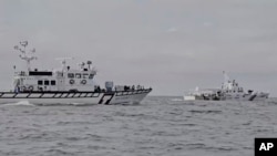 In this image from a video released by Taiwan Coast Guard Administration, a Taiwanese Coast Guard Administration ship, left, chases a Chinese Coast Guard ship near Kinmen County, Taiwan, July 11, 2024. 