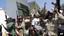 Libyan rebel fighters gesture at the former female military base in Tripoli, LIbya, August 22, 2011