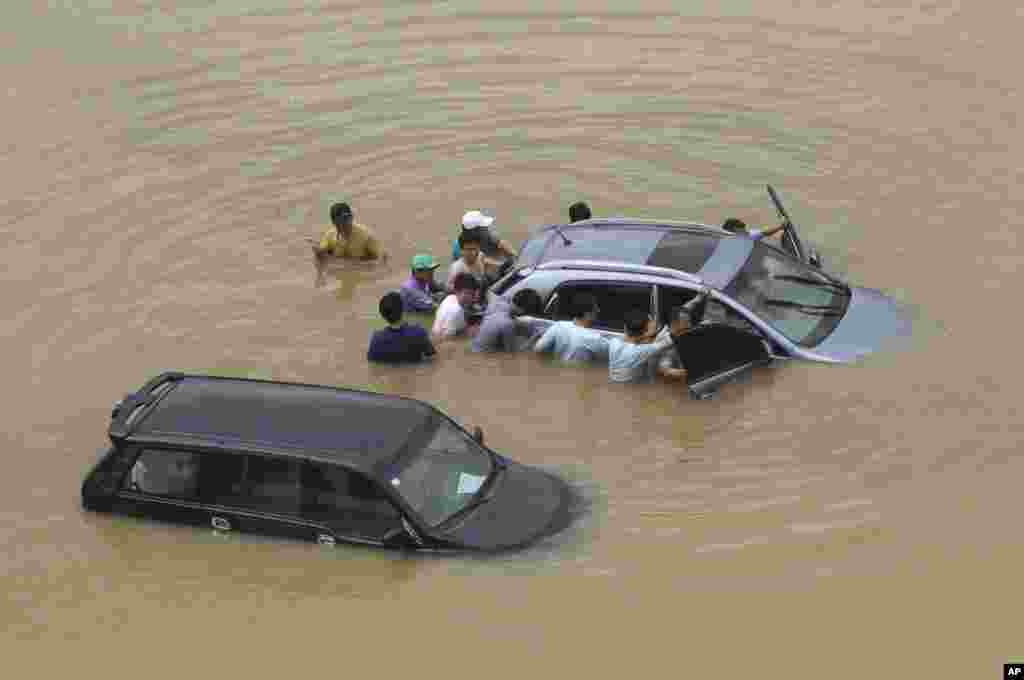 Warga Seoul mendorong kendaraan yang terendam banjir setelah hujan deras melanda wilayah metro kota Seoul, Korea Selatan.