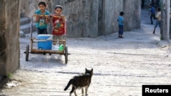 Children push a cart carrying water in the Al-Bayada neighborhood of Aleppo, Syria on April 26, 2014. 