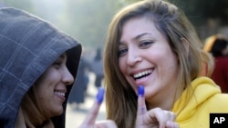 Egyptians girls show their inked fingers after casting their votes at a polling station in a referendum on a disputed constitution, Cairo, Egypt, Saturday, Dec. 15, 2012.