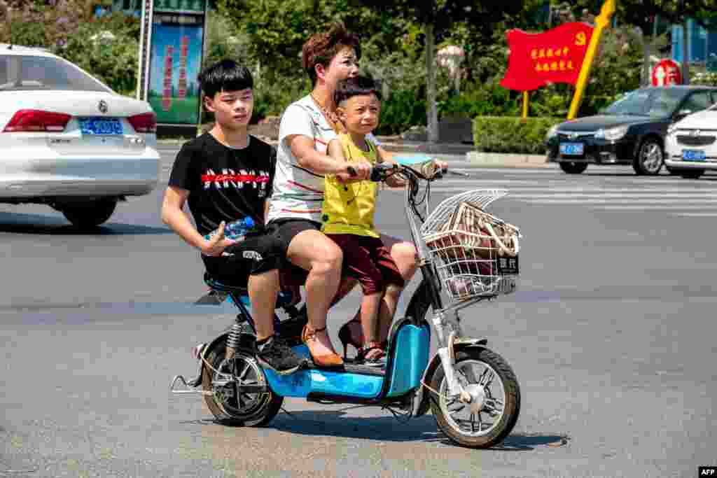 2018年8月28日，在中国河南省滑县，一名妇女带着两个孩子骑车。中国通过放宽计划生育来减缓人口老龄化的举动遇到了意想不到的障碍：许多父母不想生育更多婴儿。根据中国社科院2019年1月的报告， 中国从2011年进入快速老龄化时期，老年人口急速增加，而另一方面人口负增长期即将到来，这造成人口抚养比（劳动力人均承担的抚养人数）逐年增加，人口红利逐渐消失。