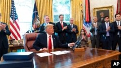President Donald Trump wraps up a phone call with the leaders of Sudan and Israel, as Cabinet officials and advisers applaud, in the Oval Office of the White House, Oct. 23, 2020, in Washington.