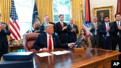 President Donald Trump wraps up a phone call with the leaders of Sudan and Israel, as Cabinet officials and advisers applaud, in the Oval Office of the White House, Oct. 23, 2020, in Washington.