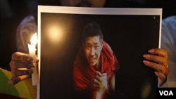 Warga Tibet di India membawa foto seorang biarawan yang tewas membakar diri, dalam aksi unjuk rasa di Bangalore (8/2).