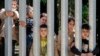 Members of a group of some 30 migrants seeking asylum are seen in Bialowieza, Poland, on May 28, 2023 across a wall that Poland has built on its border with Belarus to stop massive migrant pressure. 