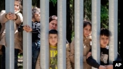 Members of a group of some 30 migrants seeking asylum are seen in Bialowieza, Poland, on May 28, 2023 across a wall that Poland has built on its border with Belarus to stop massive migrant pressure. 