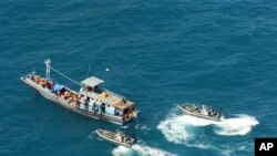 In this image provided by the Department of Home Affairs, two launches, right, from HMAS Launceston, not seen, intercept a boat, believed to be carrying 72 suspected asylum seekers, near Bathurst Island, in the Arafura Sea north of the Northern Territory