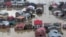 FILE - Flood-affected people row boats past partially submerged buildings in floodwaters in Srinagar, India, Sept. 9, 2014. 
